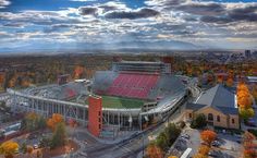 an aerial view of a football stadium in the fall with trees around it and mountains in the background