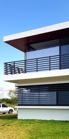 a white car is parked in front of a modern building with balconies and railings