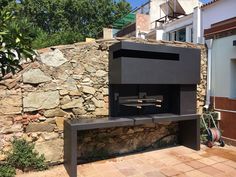 an outdoor fireplace built into the side of a stone wall