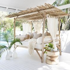 a white bed sitting on top of a wooden floor next to a lush green plant