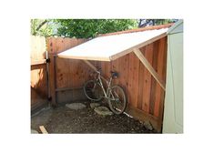 a bike is parked in front of a wooden fence with a awning over it