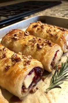 three cranberry and cheese pastries on a baking sheet with rosemary sprigs