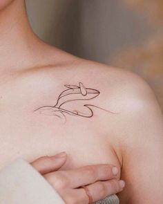 a woman's chest with a tattoo on it that has a dolphin in the water