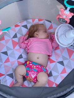 a baby laying on top of a blanket next to a fan