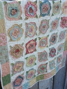 a quilt hanging on the side of a wooden fence