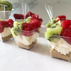 small cups filled with fruit on top of a white countertop next to cucumbers and kiwis