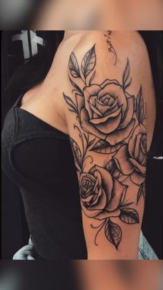 a woman's shoulder with roses and leaves tattoo on her left arm, in black ink