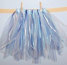 a blue tulle skirt hanging on a clothes line with two wooden pegs attached to it