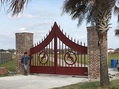 a man standing in front of a red gate that has a circular design on it