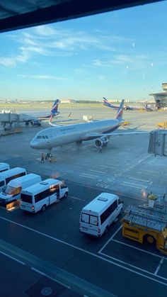 an airport filled with lots of vehicles and planes on top of tarmac next to trucks