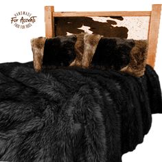 a bed with black and brown fur on top of it next to a wooden headboard