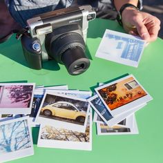 a camera sitting on top of a green table next to some pictures and cards that have been placed around it