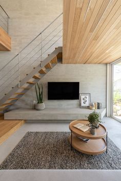 a living room with a couch, coffee table and television on the wall next to stairs