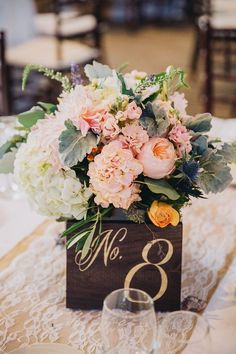 a table with a wooden sign and flowers on it, along with two wine glasses