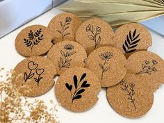 a bunch of cork coasters that have flowers and leaves drawn on them in black ink