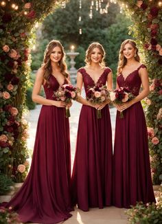 three bridesmaids in burgundy dresses standing under an archway