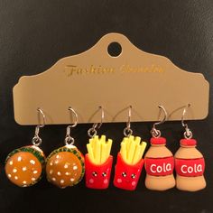 four different earrings with hamburgers, fries and ketchup on them are hanging from a hanger