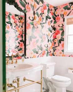 a bathroom with floral wallpaper and gold fixtures in the sink, toilet, and mirror