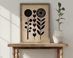 a wooden table topped with a vase next to a framed art print on the wall