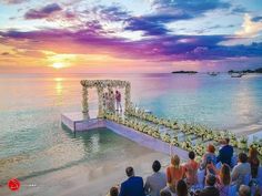 an outdoor ceremony on the beach at sunset