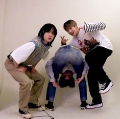 three young people posing for a photo in front of a white wall with their hands up