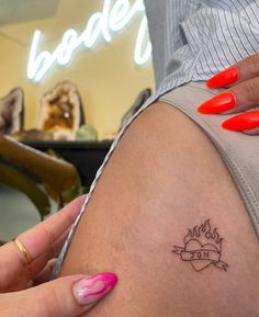 a woman's arm with a small tattoo on her left leg and red nail polish