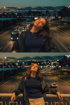 a woman standing on the side of a road in front of a city at night