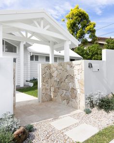 a white house with a stone wall in the front yard