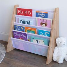 a white teddy bear sitting next to a bookshelf filled with children's books