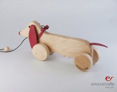 a wooden toy dog with a red leash attached to it's tail and nose