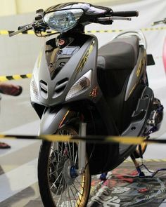 a motorcycle is parked on the floor with yellow tape around it and people standing near by