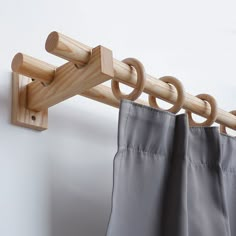 the curtain rod is attached to the wall by two wooden hooks on it's side