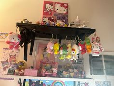 many hello kitty keychains are hanging from the ceiling above a shelf in a room