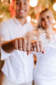 a man and woman standing in front of a christmas tree holding their hands out for the camera