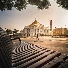 an empty park bench in front of a large building