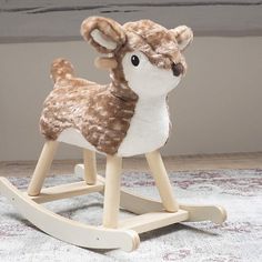 a stuffed deer sitting on top of a wooden rocking toy