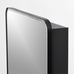 a black and silver mirror sitting on top of a white wall