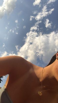 a woman with no shirt on taking a selfie in front of the sun and clouds