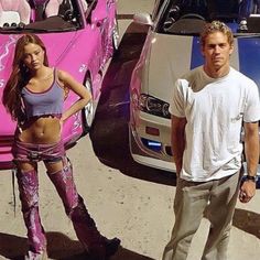 a man standing next to a woman in front of a pink car