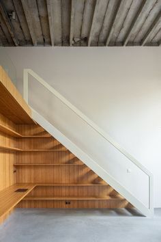 an empty room with wooden shelves under the stairs