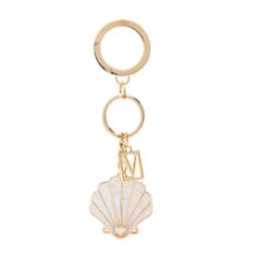 a gold key chain with a shell on the front and a letter in the middle