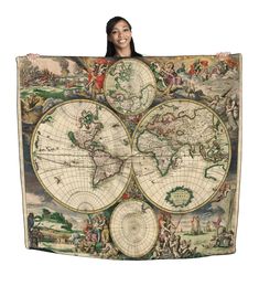 a woman holding up a large map of the world