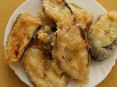 some fried food on a white plate on a yellow tablecloth with an orange cloth