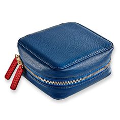 a blue leather case with zippers on the side and two red handles, sitting on a white surface