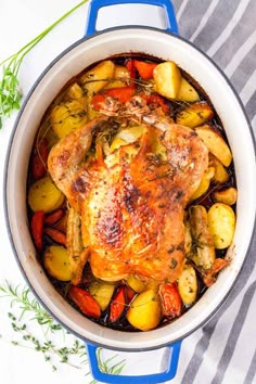 a close up of a chicken in a pot with potatoes and carrots on the side