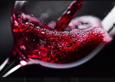 a wine glass filled with red liquid sitting on top of a table