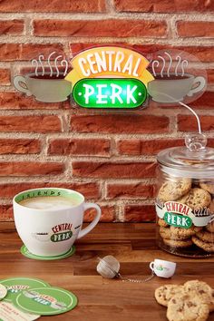 there is a cup of coffee and cookies next to the sign for central perk