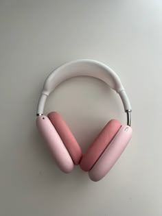 a pair of pink headphones sitting on top of a white table next to a gray wall