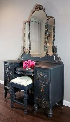 an antique vanity with mirror, stool and pink flower