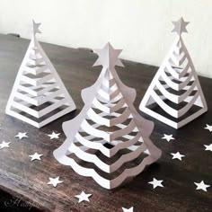 three paper christmas trees sitting on top of a wooden table